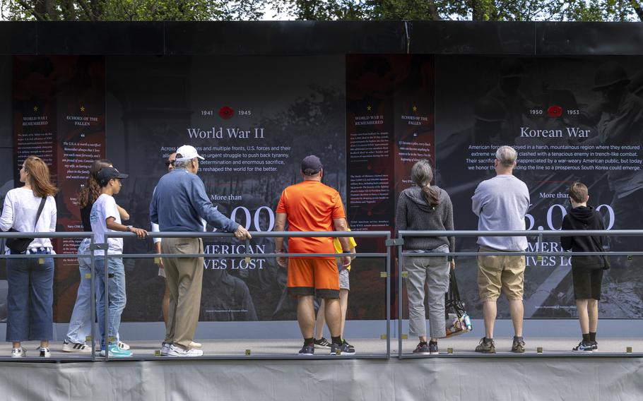 Several people standing by a railing, looking at a display.