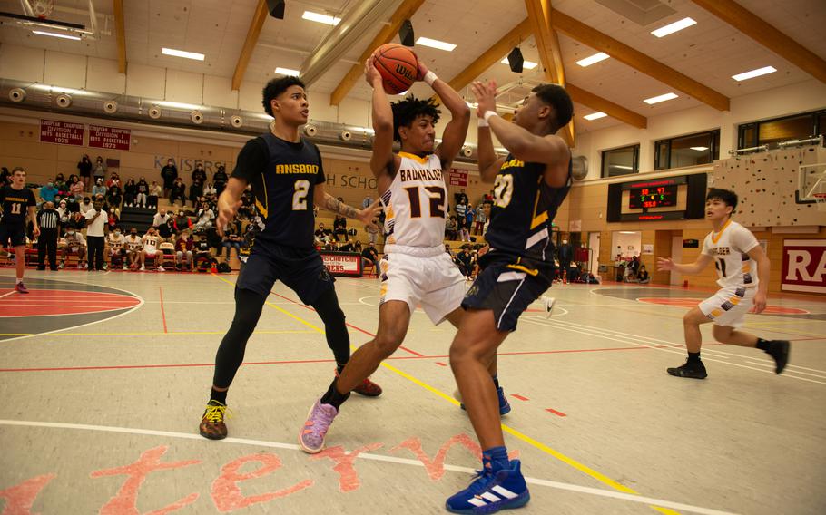 Baumholder Buccaneer Jovan Velasquez switches direction on two defenders of the Ansbach Cougars during the DODEA-Europe Division III boys basketball title game in Kaiserslautern, Germany, on Saturday, Feb. 26, 2022.
