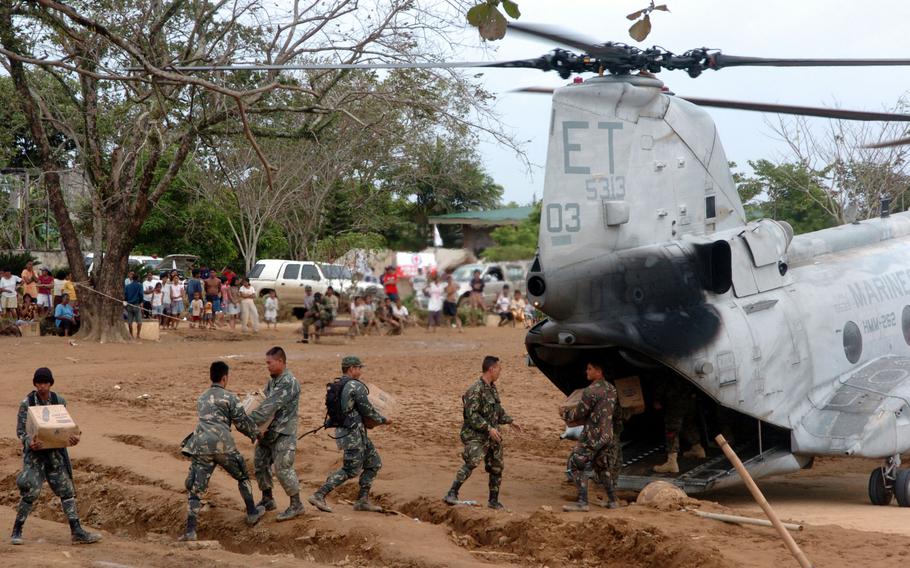 Members of the Armed Forces of the Philippines off-load relief aid from a Marine CH-46 E at Infanta, Luzon. The aid later was distributed by the AFP and aid workers.