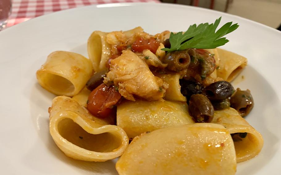 A plate of tubelike pasta sits on a table, ready to eat.