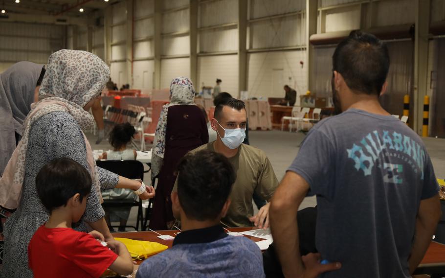 Sgt. Wyatt Ryser, combat medic, 811th Hospital Center, gives a COVID-19 briefing to an Afghan family at Camp As Sayliyah, Qatar, Aug. 20, 2021. Afghan evacuees have the option to receive a COVID-19 vaccination. 