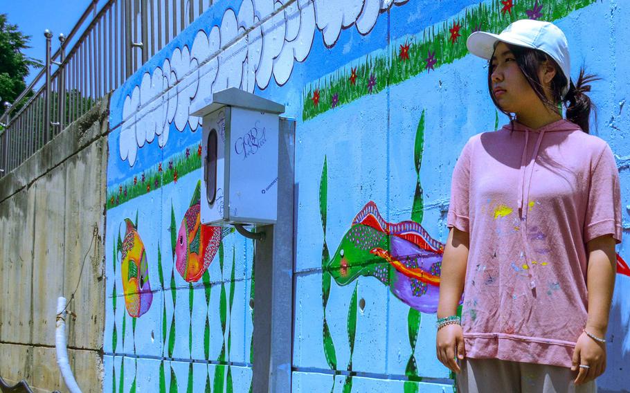 Humphreys High School junior April Conner poses in front of a mural she painted at Jacob's House, an orphanage near Camp Humphreys, South Korea, June 13, 2023.