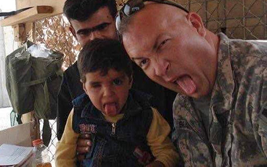 Sgt. Paul Braun sticks his tongue out with Mahdi al-Assadi, a 4-year-old boy injured in a rocket attack, while at the gate of the U.S. base at the airport in Basra, Iraq, in 2009. The boy would receive medical care in Germany and now wants to be an engineer.