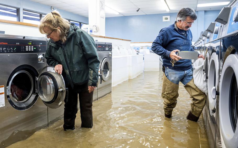 Pamela and Patrick Cerruti empty coins from Pajaro Coin Laundry as floodwaters surround machines in the community of Pajaro in Monterey County, Calif., Tuesday, March 14, 2023. “We lost it all. That’s half a million dollars of equipment,” said Pamela who added that they plan to rebuild. 