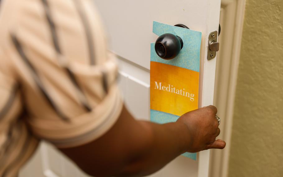 Ayana Brown, a Navy veteran, hangs a “Meditating” notice on the door nob of her meditation room at her home in San Antonio on Jan. 2, 2023. Brown is a participant of the culinary therapy program by The Pink Berets, a nonprofit that helps women service members and veterans suffering from post-traumatic stress disorder (PTSD), as well as mental and emotional trauma.