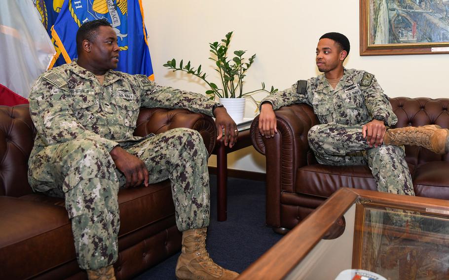 Cmdr. Hasan Abdul-Mutakallim, left, and Petty Officer 2nd Class Danny Smith talk at Naval Support Activity Naples, Italy, on March 10, 2022. They worked for different commands in the same building on the same floor at the Navy base but didn’t know they were cousins until after Smith’s father died in May 2021. 