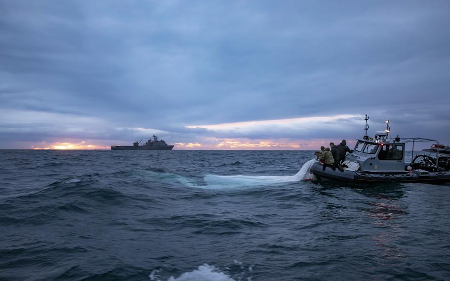 Sailors assigned to Explosive Ordnance Disposal Group 2 recover remnants of the Chinese surveillance balloon Feb. 5, 2023, off the coast of Myrtle Beach, South Carolina, while the Harpers Ferry-class dock landing ship USS Carter Hall transits nearby. 