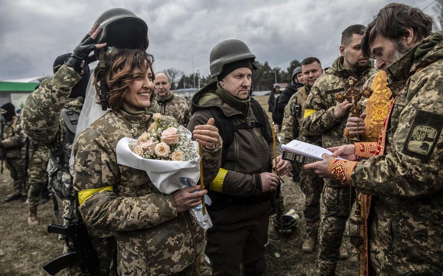 A military helmet is lifted over Filimonova at the wedding ceremony. 