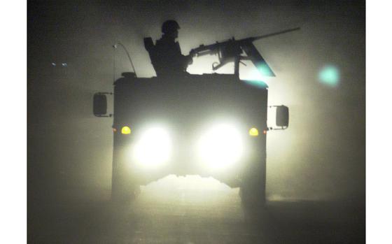 Baghdad, Iraq, October 2003: A Humvee gunner is outlined by the headlights of trailing vehicles as a convoy rolls through Baghdad on its way to a raid south of the city. Soldiers often work around the clock in what they call the Three-Block War.

META DATA: Iraq, Operation Iraqi Freedom, War on Terror,