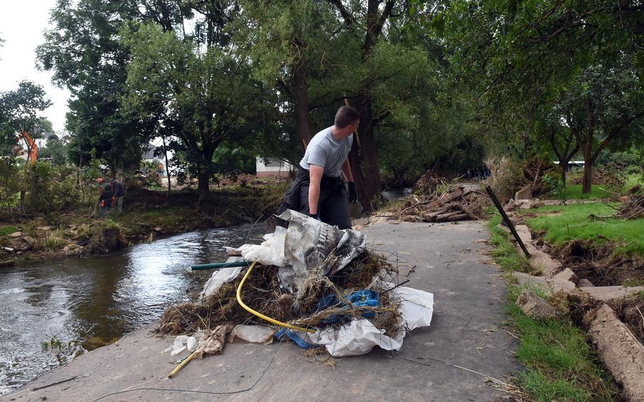 Airman Kyle Koury of Spangdahlem Air Base moves a pile of debris along a path next to the Nims River in Rittersdorf, Germany, on July 31, 2021. More than two dozen airmen from the base volunteered to help clean up the area in the aftermath of last months severe flooding in western Germany.