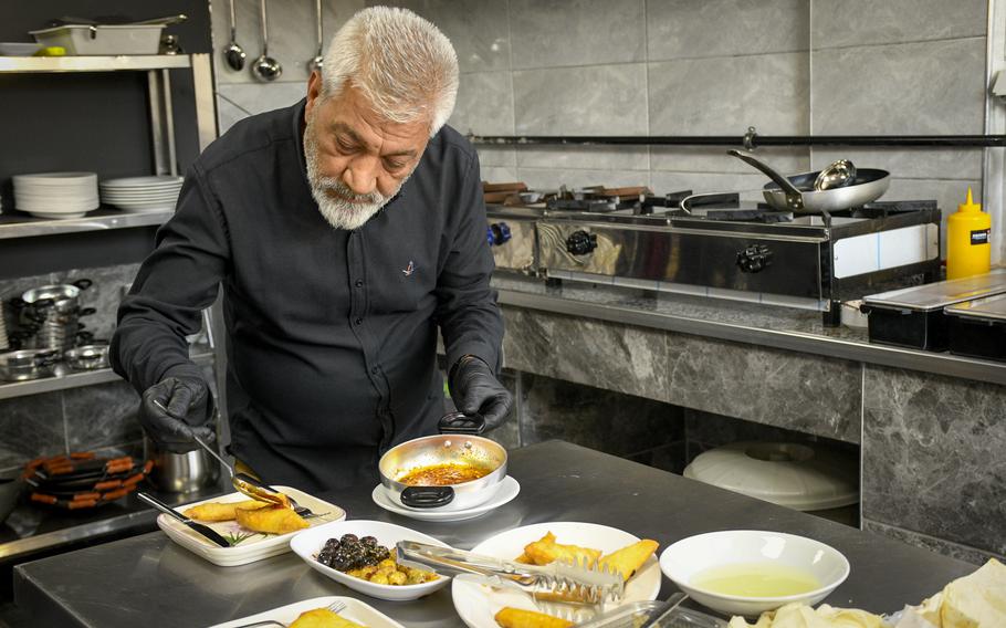 Cengiz Durmaz, owner of the Moonlight Restaurant outside of Incirlik Air Base, Turkey, spoons garlic sauce onto borek, a fried pastry filled with chicken, on Feb. 24, 2023.