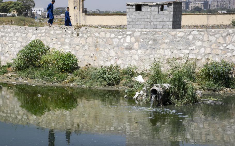 Two boys walk past a pipe where untreated sewage pours into the Kabul River near the Makroyan Waste Water Treatment Plant in Kabul, Afghanistan, Aug. 16, 2020. 