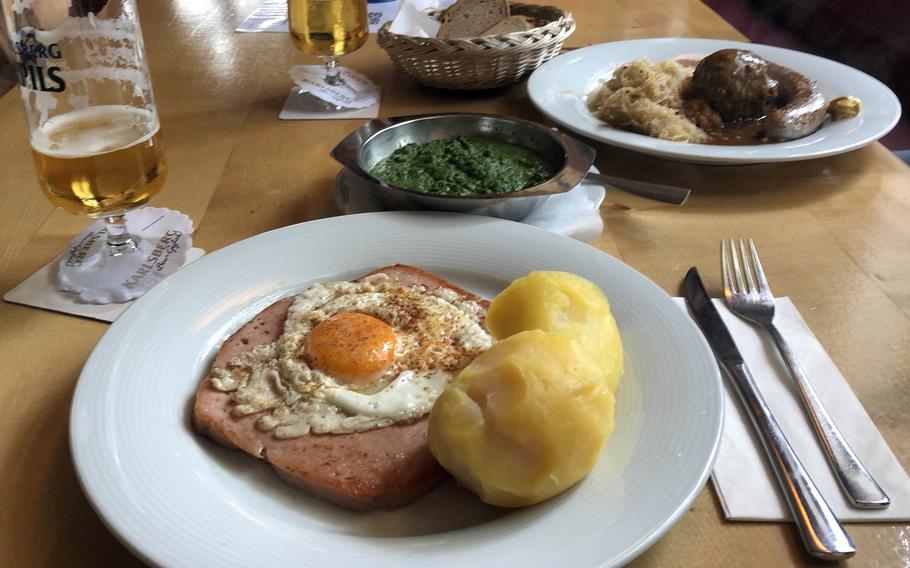 The fleischkaese served at the Wurst-Kuech in Kaiserslautern, Germany, is topped with a fried egg and served with spinach and boiled potatoes. The Pfaelzer Teller, upper right, is a plate of specialties from the Pfalz region. 