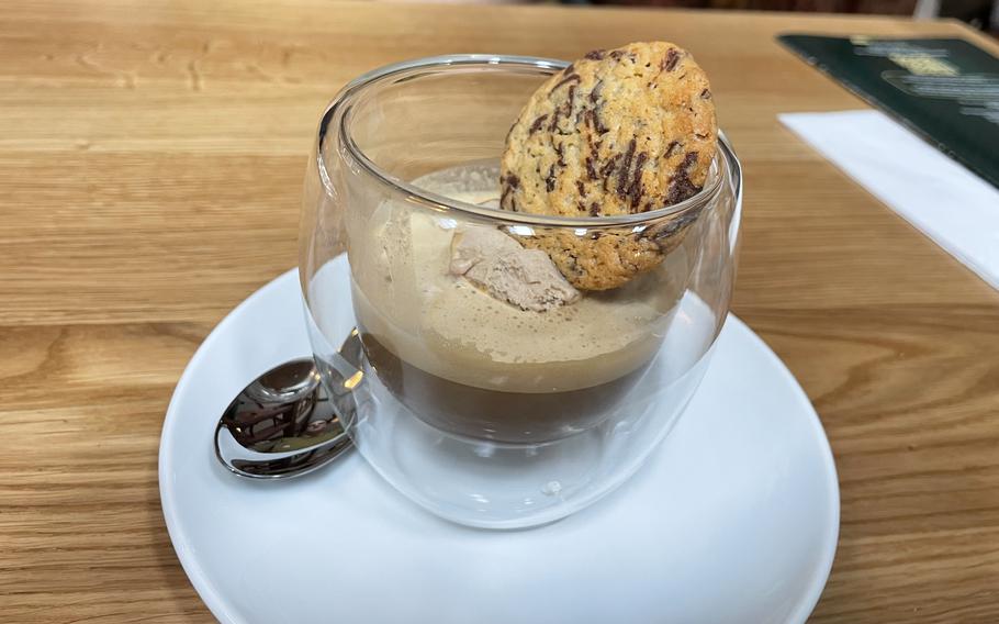 A cup of espresso topped with a scoop of ice cream and a cookie in a glass cup.