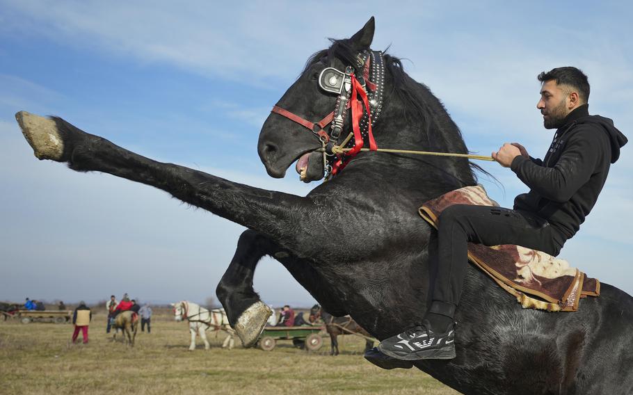 A man shows off riding skills during Epiphany celebrations in the village of Pietrosani, Romania, Thursday, Jan. 6, 2022. According to the local Epiphany traditions, following a religious service, villagers have their horses blessed with holy water then compete in a race. 