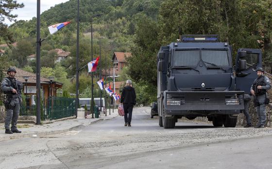A local Serb man walks past Kosovo police officers securing the area around the Banjska monastery in the village of Banjska, Kosovo on Wednesday, Sept. 27, 2023. Police on Wednesday allowed media into the village of Banjska, where a daylong shootout between armed Serbs and Kosovar police on Sunday left one officer and three gunmen dead. (AP Photo/Visar Kryeziu)