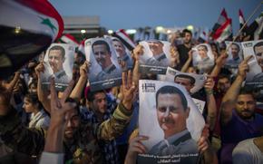 Syrian President Bashar Assad supporters hold up national flags and pictures of Assad as they celebrate at Omayyad Square, in Damascus, Syria, Thursday, May 27, 2021. (AP Photo/Hassan Ammar)