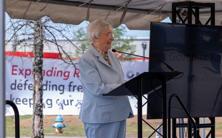 A woman in a white suit speaks at a podium.