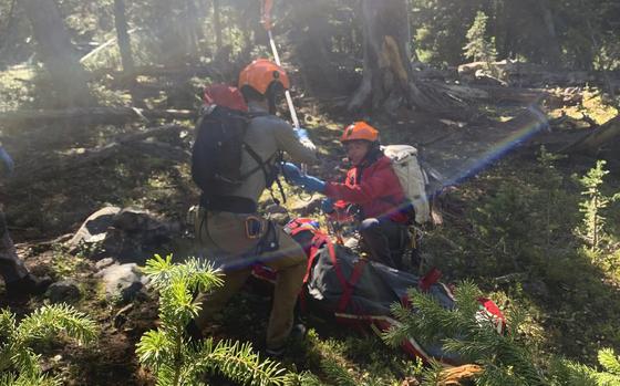 In this photo provided by the Gallatin County, Mont., Sheriff Search and Rescue, members of the search and rescue team hook up rope hanging from a rescue helicopter to a basket holding Rudy Noorlander after Noorlander was mauled by a grizzly bear that bit off his lower jaw, Friday, Sept. 8, 2023. The attack happened in the Custer Gallatin National Forest about 55 miles north of Yellowstone National Park. Noorlander remained hospitalized, Monday, Sept. 11. His daughter said he's doing well, but is expected to be there through October for surgeries. (Gallatin County Sheriff Search and Rescue via AP)