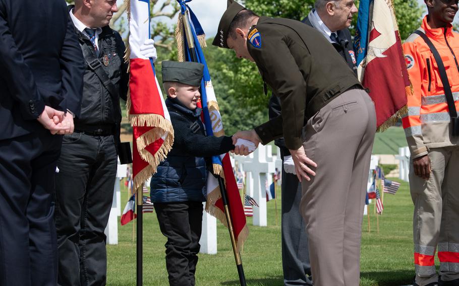 The general bends down to shake the young boy’s hand.