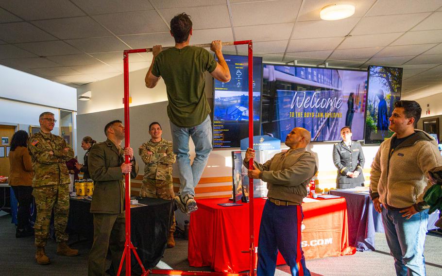 A college student does pull ups in front of military recruiters.