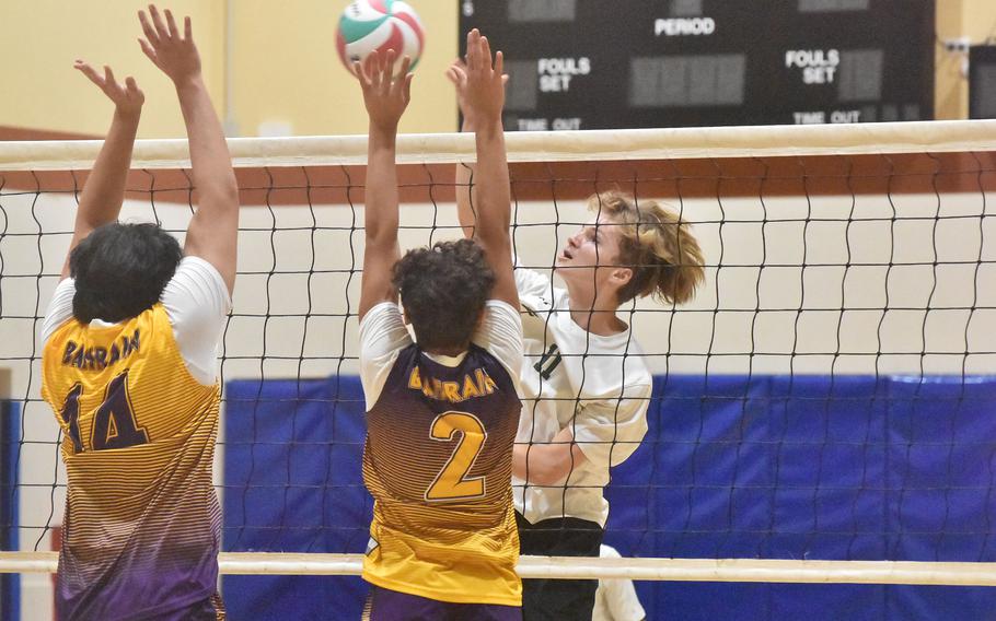Naples’ Nathan Mellor tries to hit through the Bahrain block of Nick Beaumont, left, and Diego Mercado-Rodriguez during pool-play action Thursday, Oct. 26, 2023, in the DODEA-Europe boys volleyball championships.
