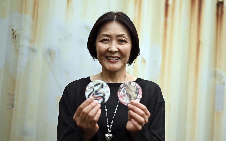 A woman holds up car sticker decals featuring colorful animal designs.