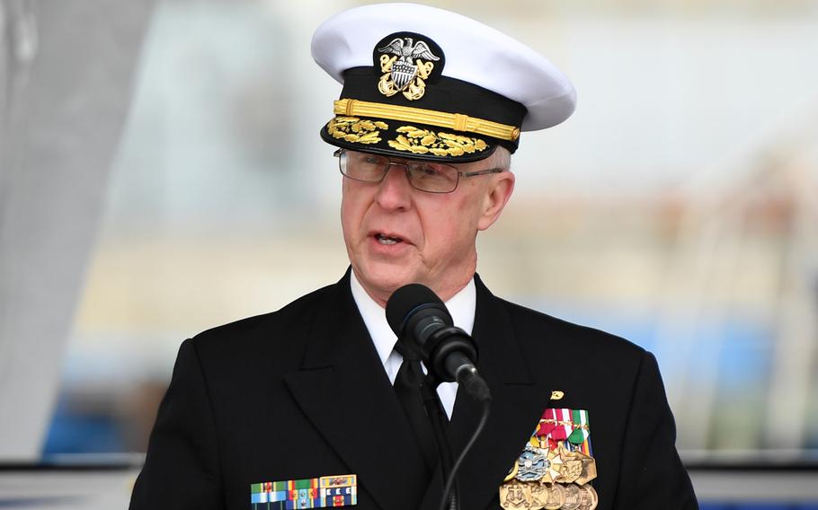 A sailor speaks in a microphone during a ceremony