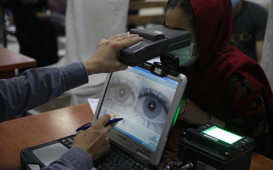 An employee scans the eyes of a woman for biometric data needed to apply for a passport, at the passport office in Kabul, Afghanistan, Wednesday, June 30, 2021. Afghans are lining up by the thousands at the Afghan Passport office to get new passports.