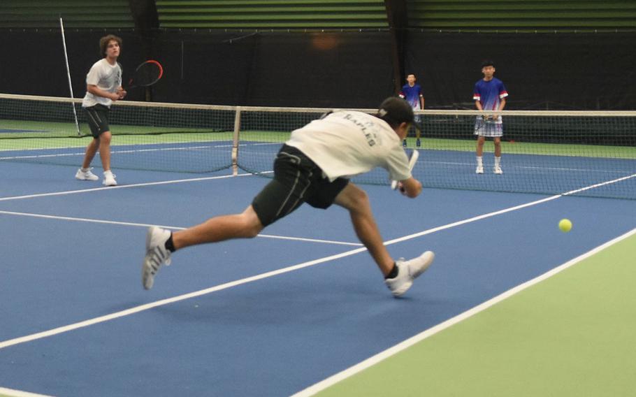 Naples' Ben Avalos lunges for the ball while teammate Nicholas Cruz looks on during a semifinals doubles match against Ramstein on Friday, Oct. 21, 2022, at the DODEA European tennis championships in Wiesbaden, Germany.