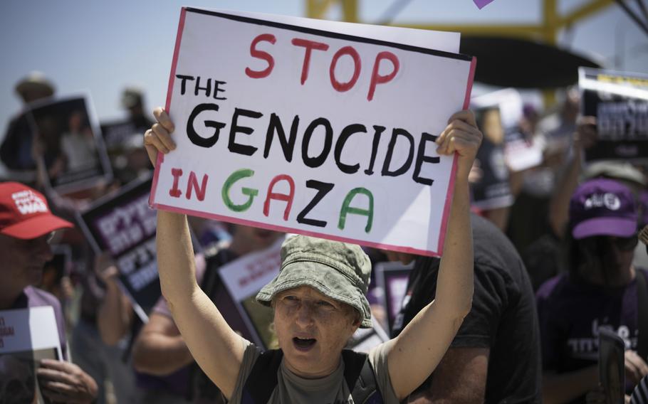 A protestor holding a sign that reads “Stop the Genocide in GAZA.”