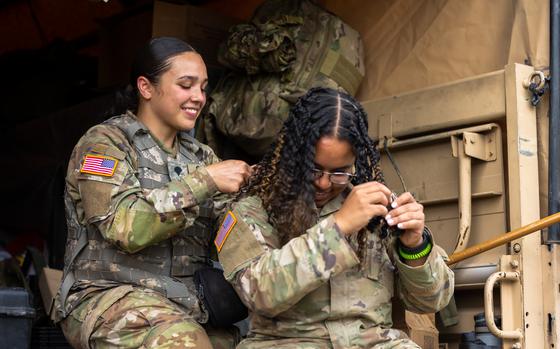 Spec. Rosealina Ortiz (left) assists Spec. Oscarina Pepen with her hair following live fire training at CFB Gagetown, New Brunswick, Canada, August 9, 2022.