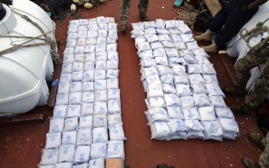 U.S. service members from coastal patrol ship USS Tempest and USS Typhoon gather confiscated illegal drugs aboard a stateless dhow vessel apprehended while transiting international waters in the Arabian Sea, Dec. 27, 2021. 