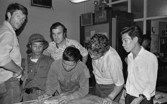 The last three staffers in The Associated Press’ Saigon bureau, reporters Matt Franjola, left, Peter Arnett, rear, and George Esper, second from right, are joined by two North Vietnamese soldiers and a member of the Viet Cong.