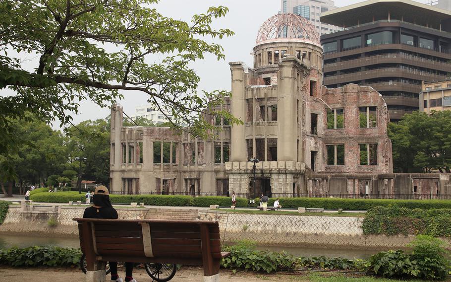 A woman sits on a bench across from the iconic Atomic Bomb Dome in Hiroshima, Japan, Aug. 7, 2020. 