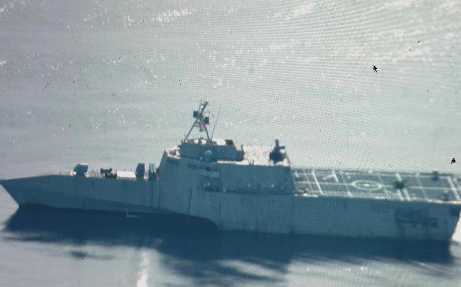 A gray U.S. Navy destroyer sailing through blue ocean waters under a partly cloudy sky. 