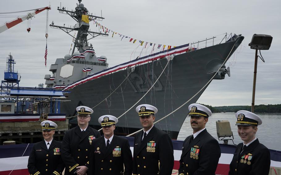 Naval officers pose in front of a warship named for Sen. Carl M. Levin, D-Michigan, Saturday, Oct. 2, 2021, at Bath Iron Works in Bath, Maine. The Arleigh Burke class destroyer was christened on Saturday. (AP Photo/Robert F. Bukaty)