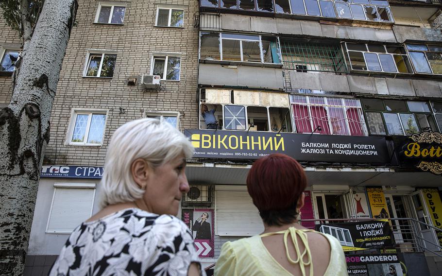 People stand outside a residential building in Nikopol that was damaged by a Russian strike early on the morning of Aug. 19, 2022.