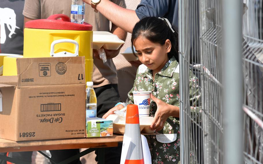 A girl gets a to-go box for lunch inside temporary living facilities for Afghan evacuees at Ramstein Air Base, Germany, on Saturday, Aug. 21, 2021.