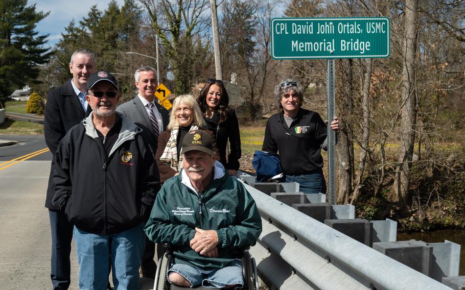 From left, Rep. Brian Fitzpatrick, Rich Homa, Commissioner Bob Harvie, Commissioner Diane Marseglia, Dennis Best, Middletown Township Supervisor Bernadette Hannah and Ed Preston pose for a group photo Saturday, March 18, 2023, near signage on the newly dedicated Cpl. David John Ortals, USMC Memorial Bridge.