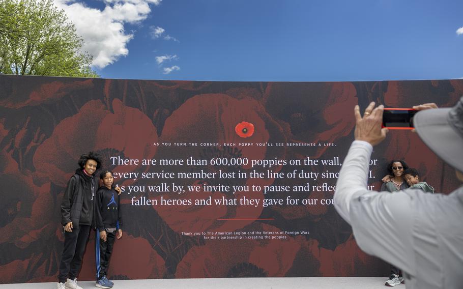 People pose for a photo against a display explaining USAA’s Poppy Wall of Honor.