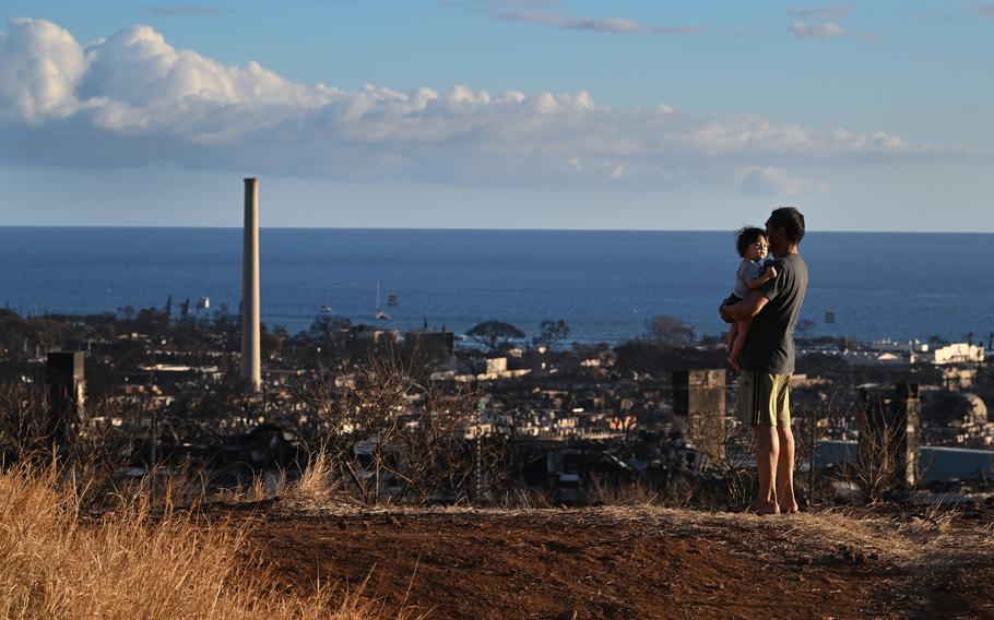 A man and child look at fire damage in Lahaina, Hawaii, on Aug. 13, 2023