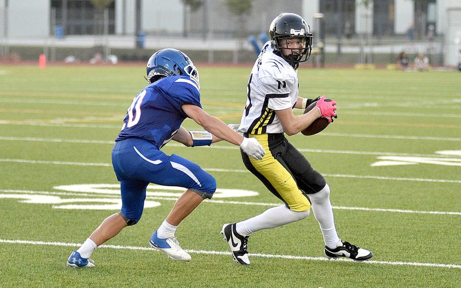 Stuttgart receiver Jackson Boggs turns after catching a pass during a Sept. 8, 2023, game at Ramstein High School on Ramstein Air Base, Germany. Going for the tackle is the Royal senior Jayden Andrews.