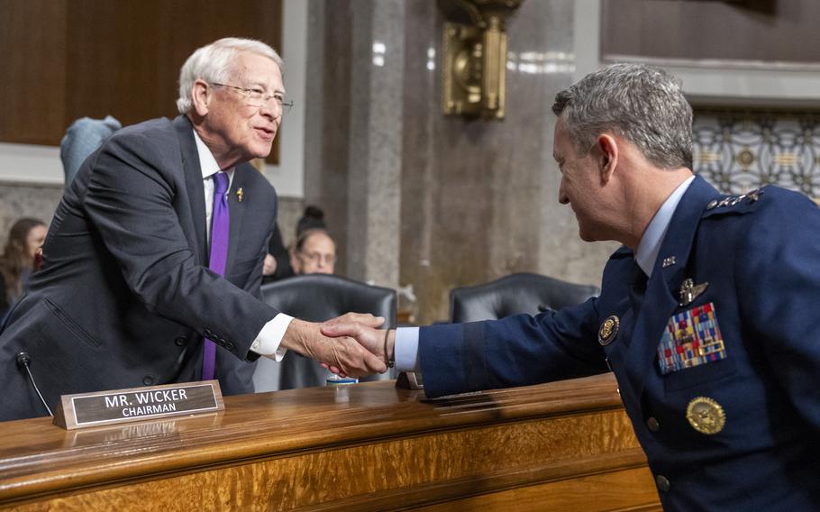 Wicker and Caine standing over a table and shaking hands.