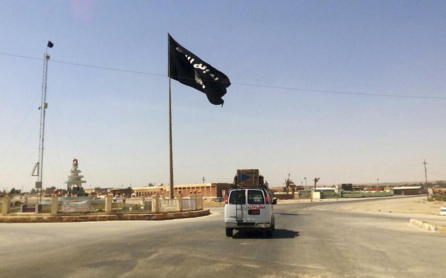 A motorist passes by a flag of the Islamic State group in central Rawah, 175 miles northwest of Baghdad, Iraq, July 22, 2014. A senior U.S. official said Wednesday the world must remain vigilant about the continued threat posed by the Islamic State group around the globe — especially in Africa — a reminder of an unfinished war despite the overwhelming preoccupation with the conflict in Ukraine.