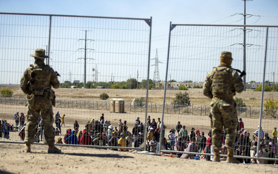 Migrants wait in line adjacent to the border fence under the watch of the Texas National Guard to enter into El Paso, Texas, Wednesday, May 10, 2023. U.S. authorities say an 8-year-old girl died Wednesday, May 17,  in Border Patrol custody, a rare occurrence that comes as the agency struggles with overcrowding. The Border Patrol had 28,717 people in custody on May 10, the day before pandemic-related asylum restrictions expired, which was double from two weeks earlier, according to a court filing.