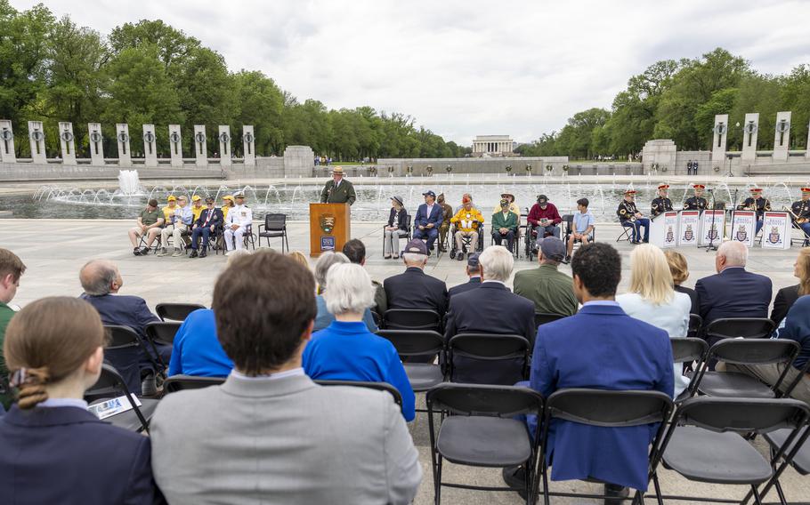 A man at a podium addresses a seated crowd at a ceremony.