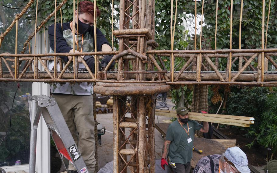 Kieran Beam, left, works on the train tracks as part of the preparations for the annual Holiday Train Show at the New York Botanical Garden in New York, Thursday, Nov. 11, 2021. The show, which opens to the public next weekend, features model trains running through and around New York landmarks, recreated in miniature with natural materials.