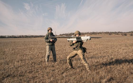 A Ukrainian soldier who goes by the call sign Ulysses stands by as his fellow soldier, Denys, prepares to launch a reconnaissance drone in February in the Donetsk region in Ukraine.