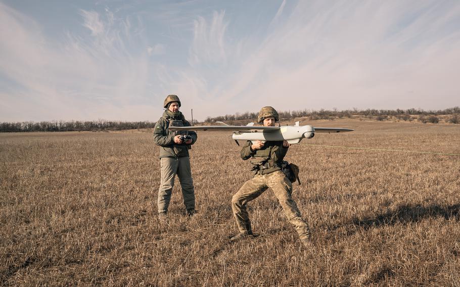 A Ukrainian soldier who goes by the call sign Ulysses stands by as his fellow soldier, Denys, prepares to launch a reconnaissance drone in February in the Donetsk region in Ukraine.